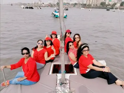 A large group of guests in matching red seated along the bow under sail